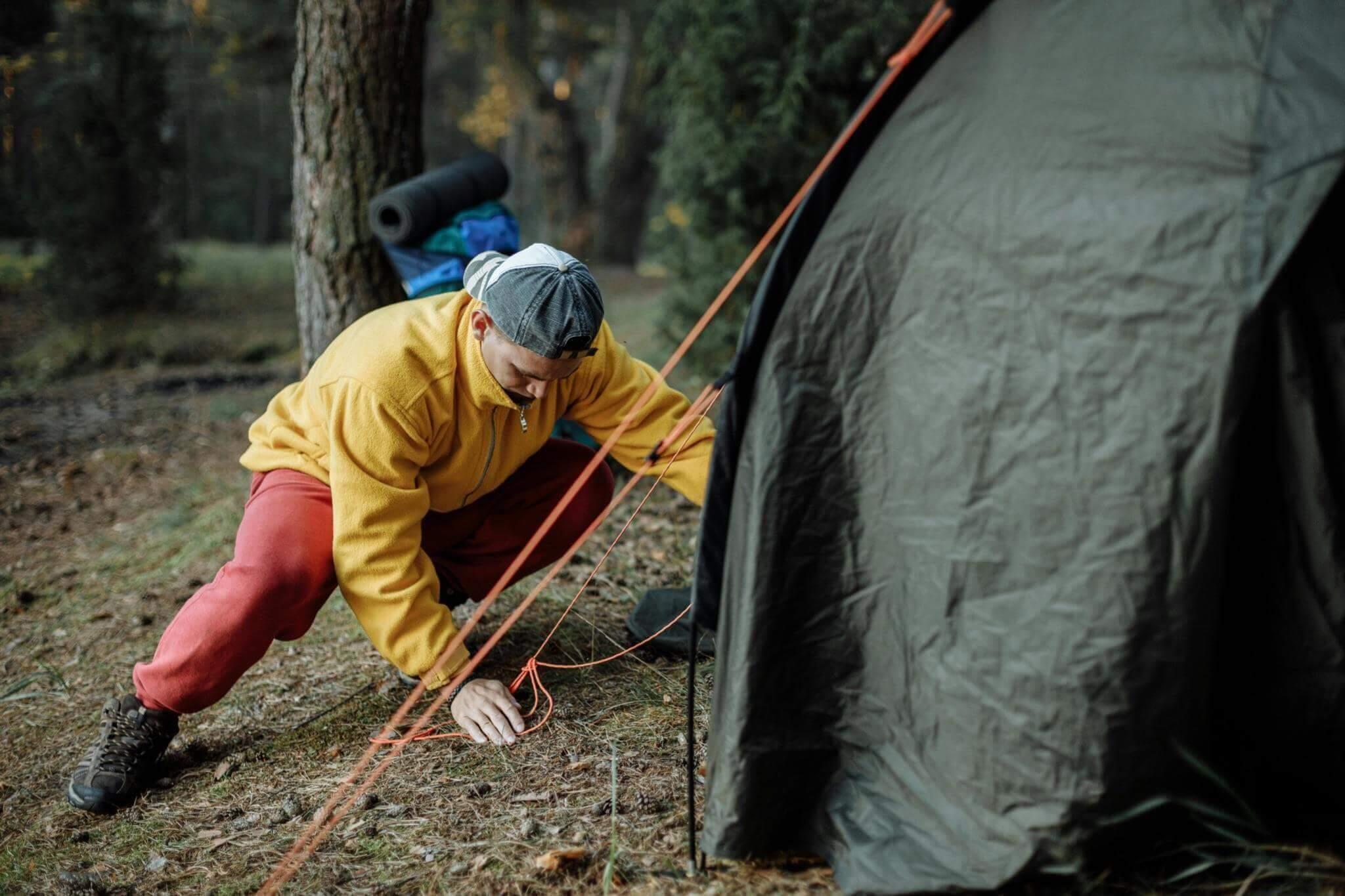 Man in yellow jacket beside tent on camping trip