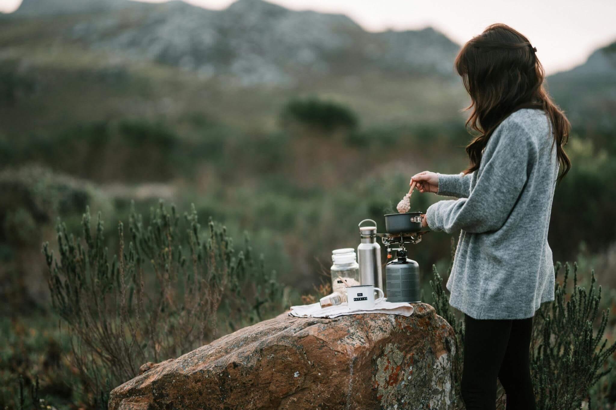 Woman standing by large rock on off-grid family camping trip