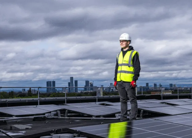 Man standing on roof beside solar panels