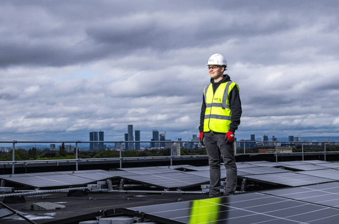 Man standing on roof beside solar panels