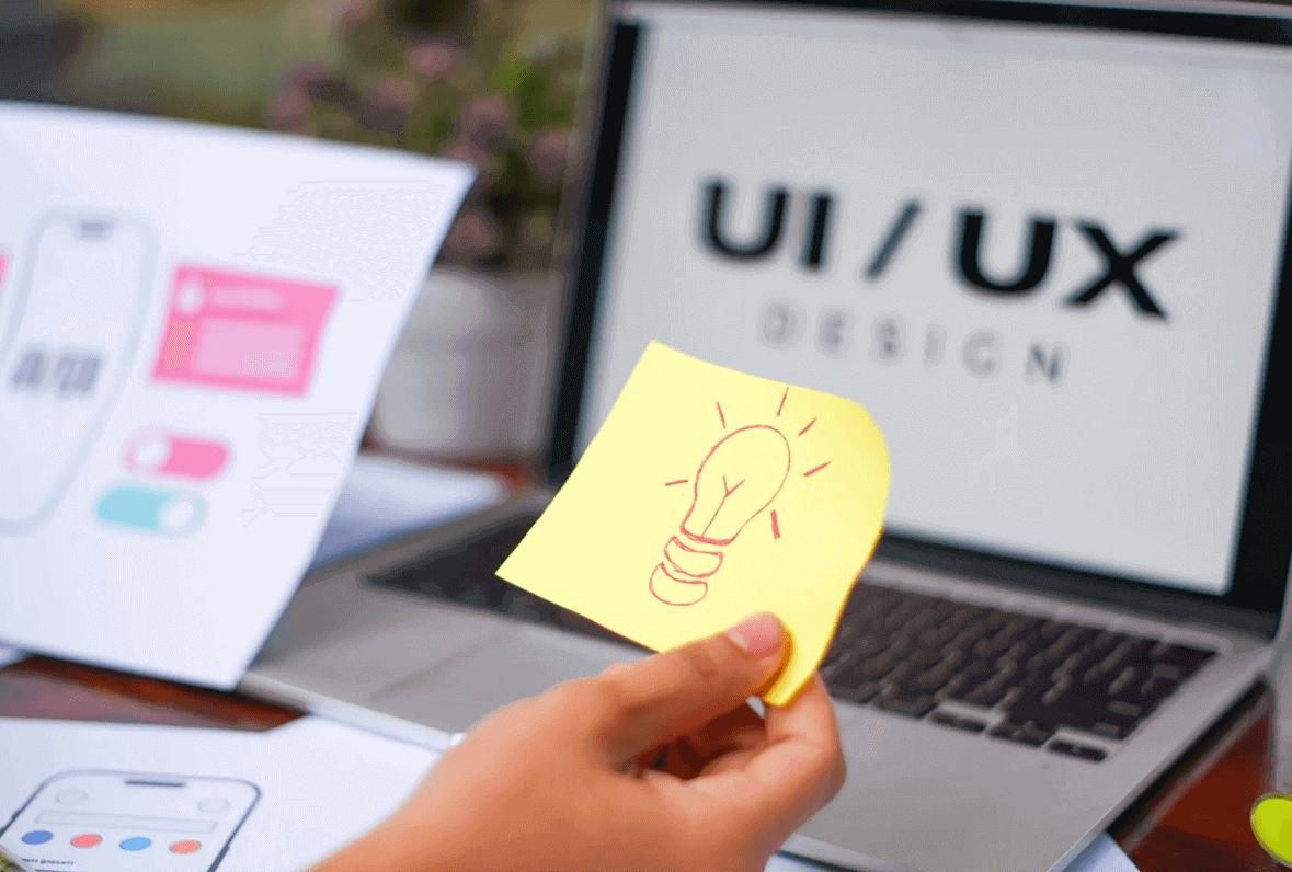 How UX Agencies Shape Executive Decisions 2 Person holding paper near laptop in UX agency meeting